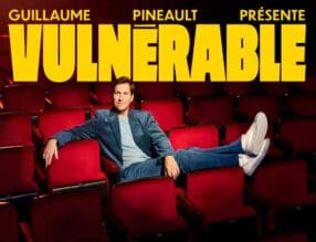 Affiche du nouveau spectacle de Guillaume Pineault, Vulnérable. L'humoriste pose assis dans une salle de salle de spectacle